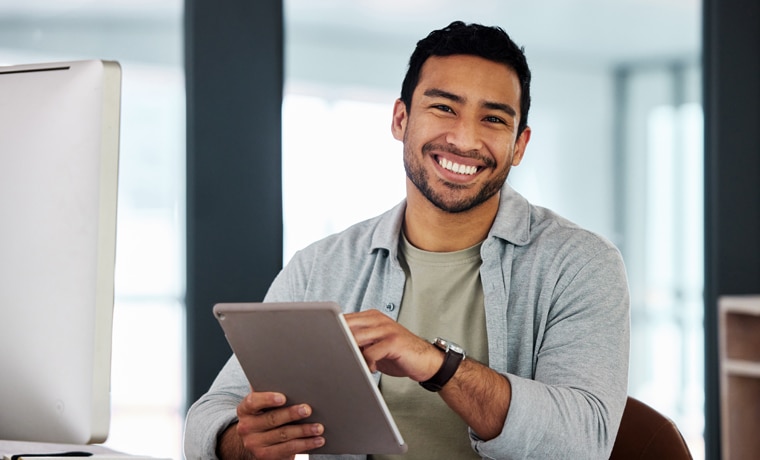 Smiling man holding tablet in modern office workspace, dental practice setting