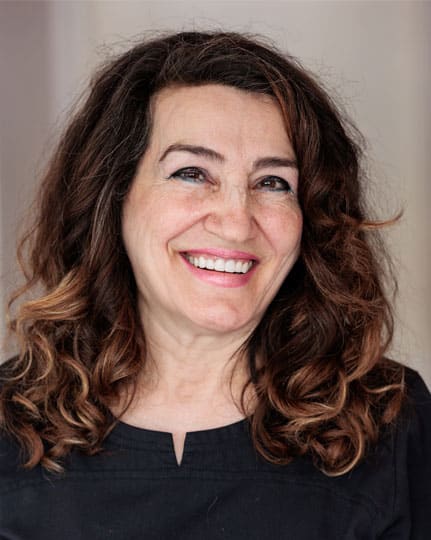 Woman with wavy brown hair smiling at camera in professional headshot for orthodontics practice.