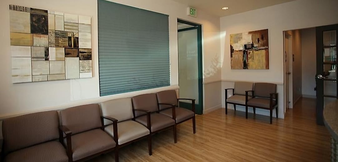 Modern orthodontic office waiting room with seating, educational displays, and reception desk area.