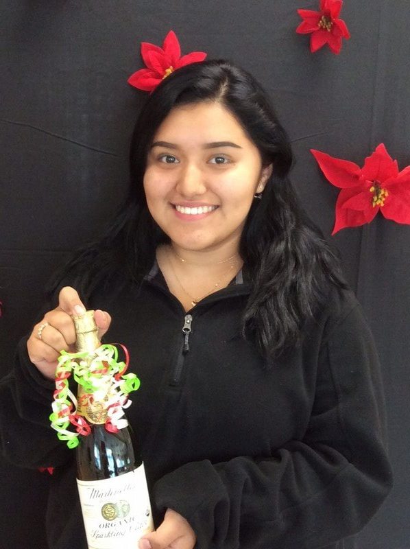 Young woman holding holiday ornament against dark background with red decorative bows.
