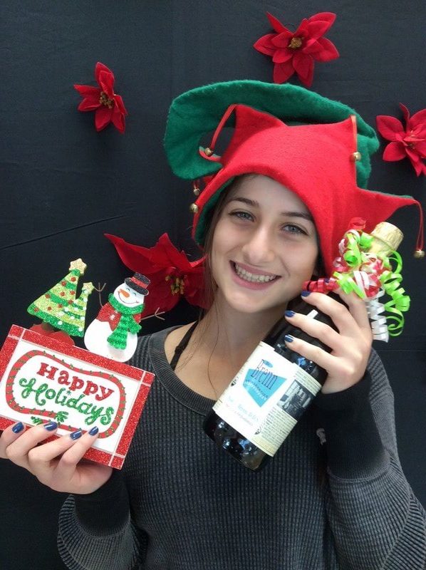 Young woman in holiday attire holding dental products against festive black background with red decorations.