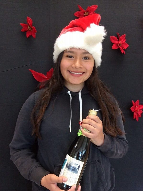 Woman wearing Christmas hat and holding wine bottle at Brenn Orthodontics holiday event