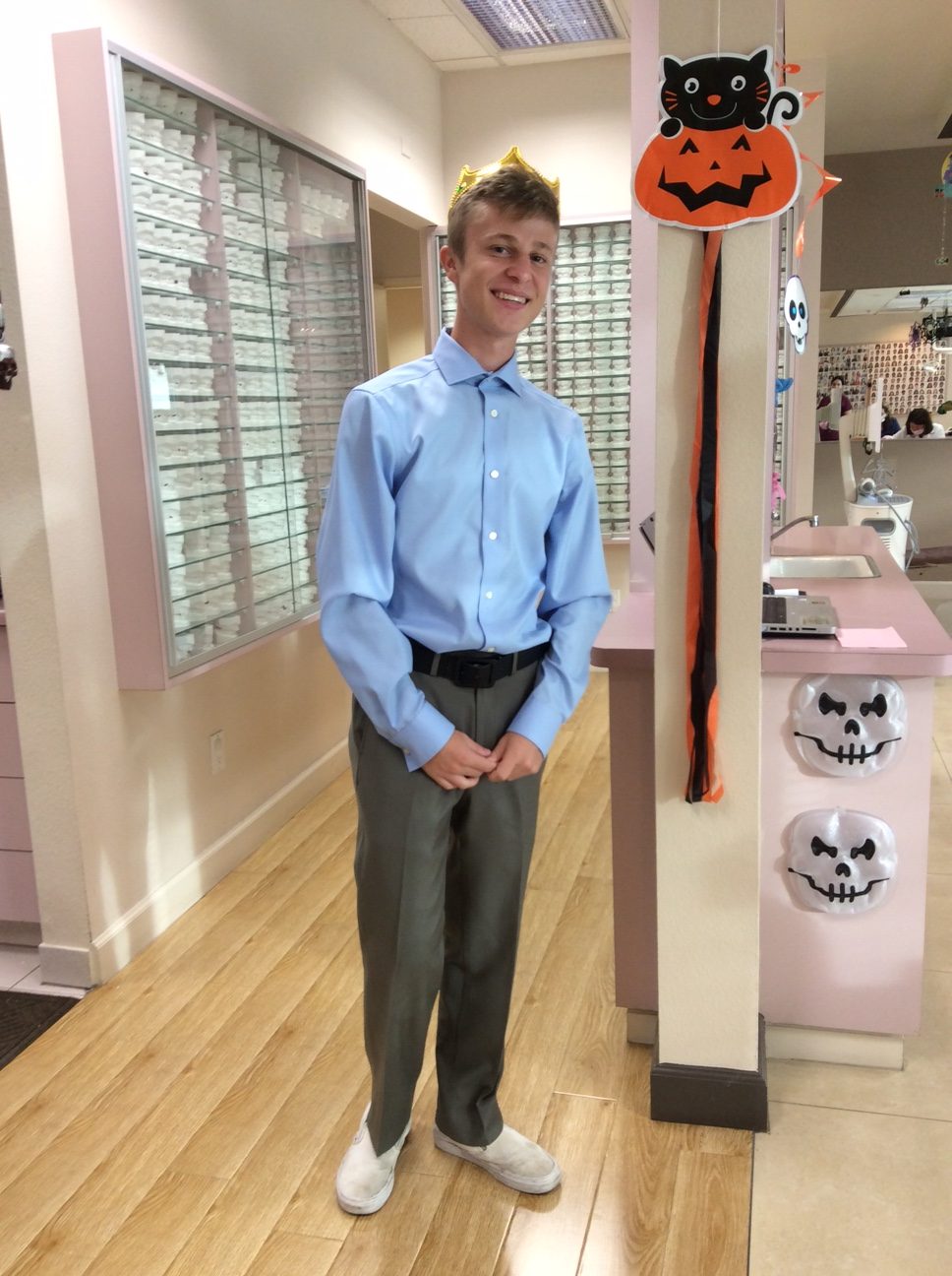 Young man in blue shirt standing in orthodontic office with Halloween decorations.