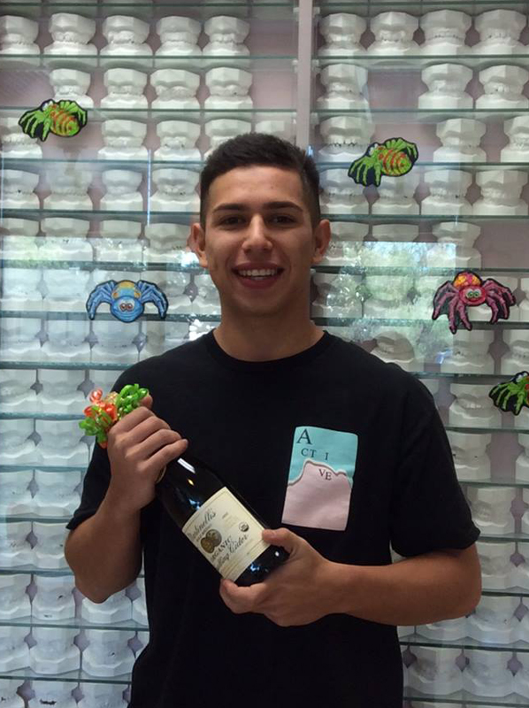 Man holding skincare products in front of shelves of beauty supplies in retail setting.