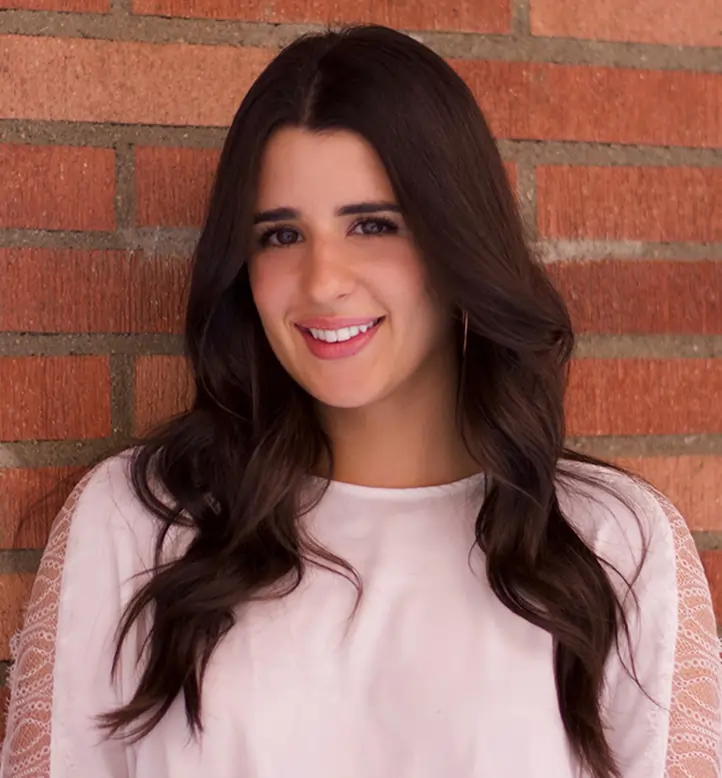 Woman smiling at camera against brick wall for orthodontics practice portrait